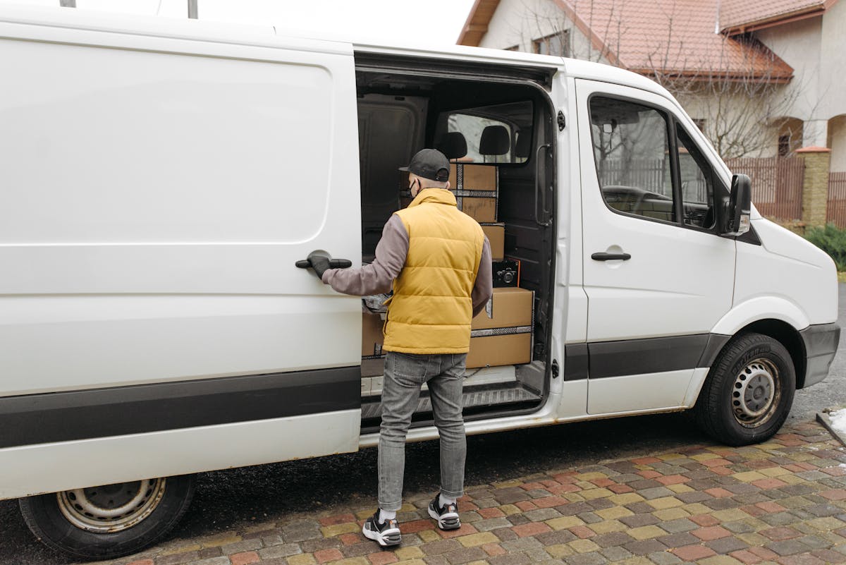 DHL Abholung – Paketfahrer lädt Sendungen in Lieferwagen