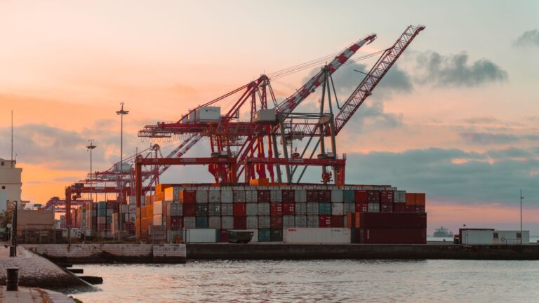 Digitale Lieferketten – Containerkräne im Hafen bei Sonnenuntergang