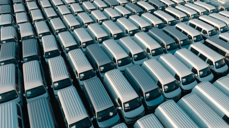 Effizientes Fuhrparkmanagement: Wie Logistikunternehmen ihre Betriebskosten in den Griff bekommen Effizientes Fuhrparkmanagement – Transporter-Flotte in Reihen geparkt