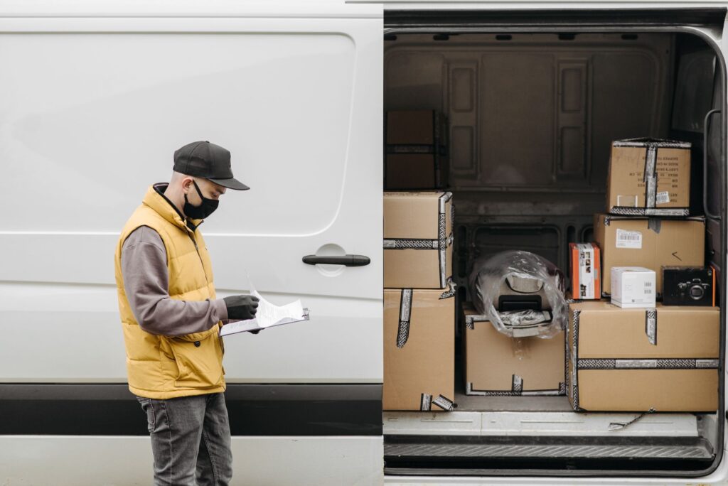 DHL Sendung abgeholt – Paketfahrer prüft Sendungen am Lieferwagen
