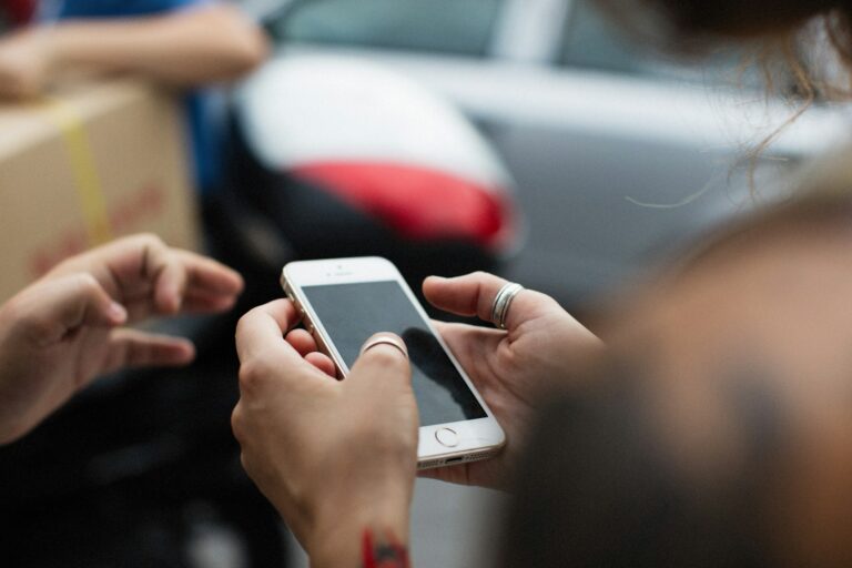 Sendung elektronisch angekündigt – Hände mit Smartphone neben einem Paket