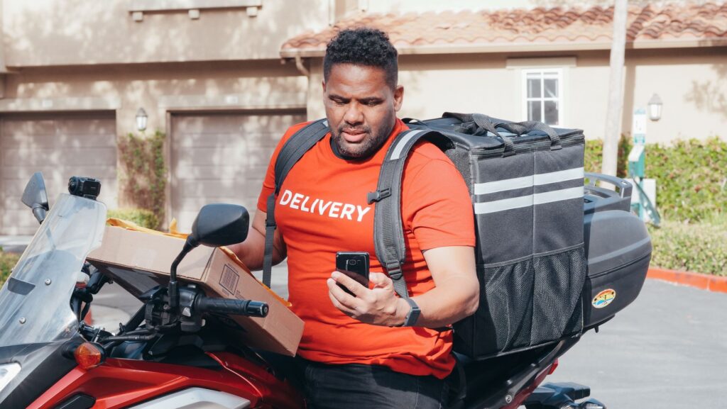 SEUR Tracking – Kurier mit Motorrad und Smartphone bei der Sendungsprüfung