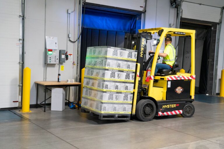 arbeitsbühne mieten – A warehouse employee operating a forklift to move stocked goods indoors. Perfect for industry and