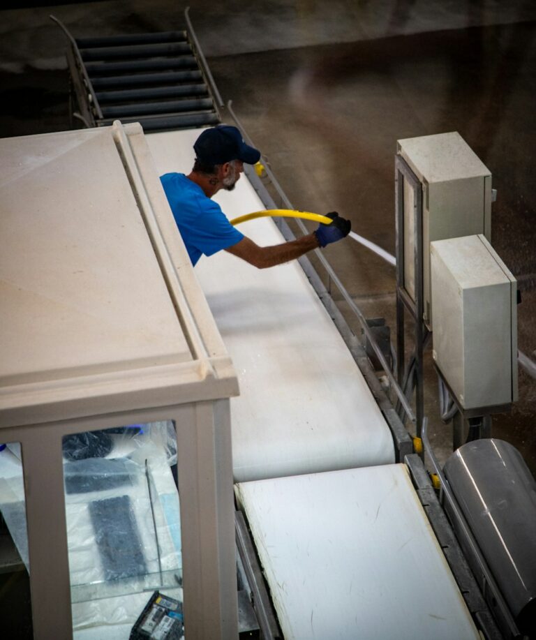 Saubere Werkstatt, weniger Ausfälle: Worauf es bei Ordnung und Instandhaltung wirklich ankommt Industrial worker spraying a dusty conveyor belt system.