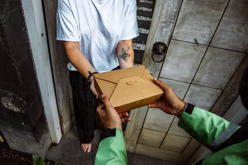 Paket nach Neuseeland, Kurier &uuml;bergibt ein Paket an der Haust&uuml;r