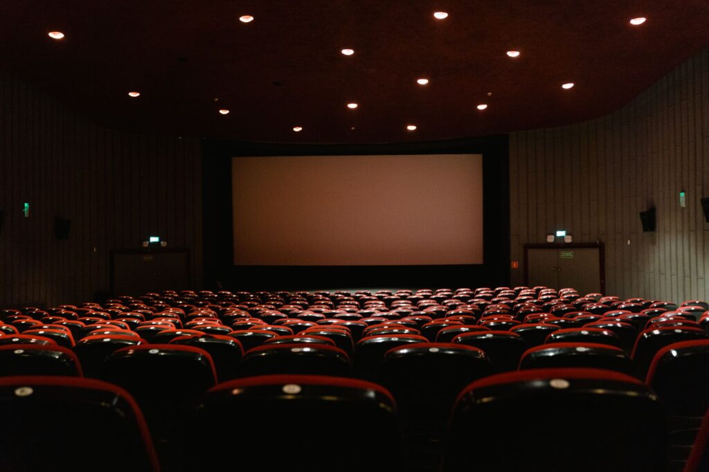 Espressomaschine im Kino – leerer Kinosaal mit roten Sesseln vor der Leinwand