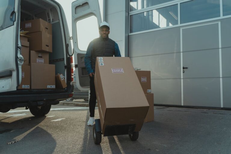 Logistik für KMU: Wie kleine Betriebe Wege, Lager und Lieferungen im Griff behalten Logistik für KMU – Lieferant entlädt Pakete mit Sackkarre aus einem Transporter
